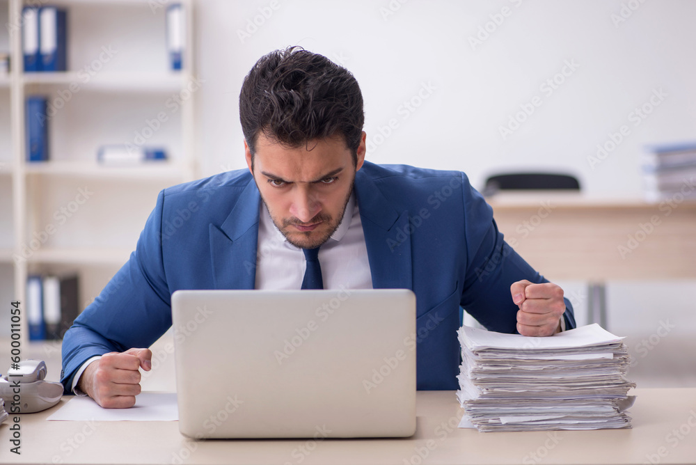 Young male employee and too much work in the office Young male employee and too much work in the office