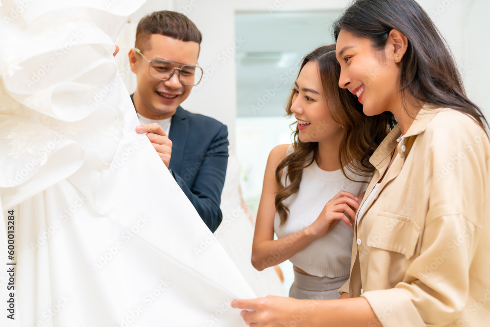 Beautiful Asian woman lesbian couple choosing wedding dress for marriage ceremony in bridal shop together. Diversity sexual equality, lgbtq, pride day, marriage equality, Same-sex marriage concept. Beautiful Asian woman lesbian couple choosing wedding dress for marriage ceremony in bridal shop together. Diversity sexual equality, lgbtq, pride day, marriage equality, Same-sex marriage concept.