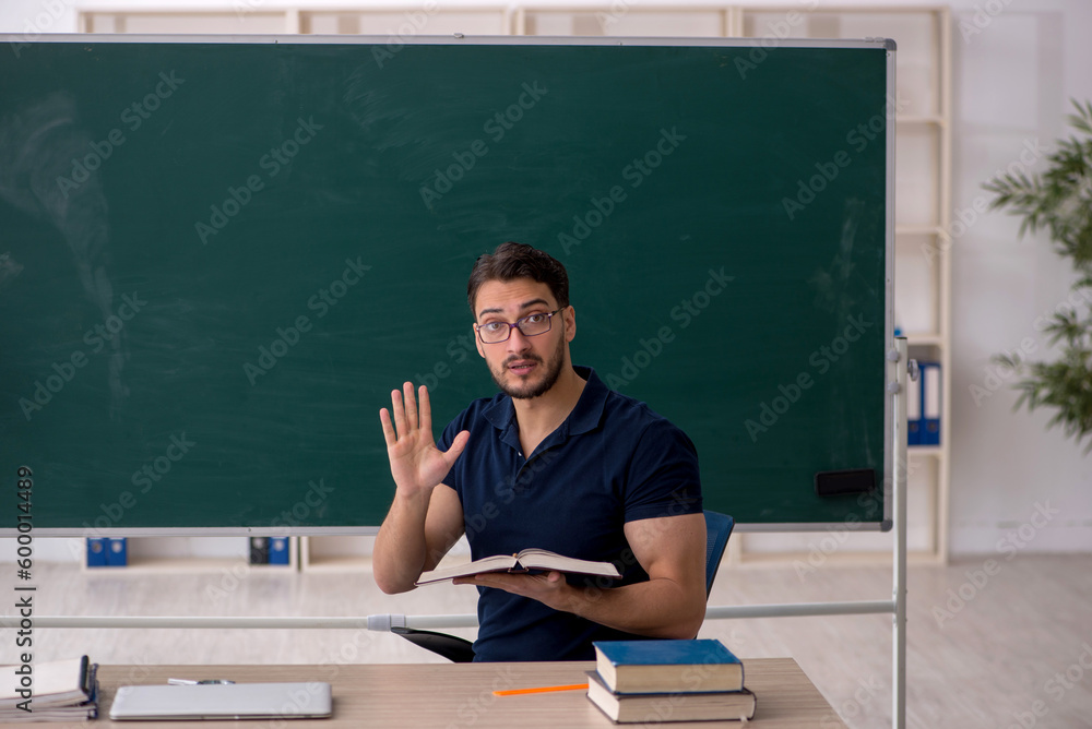 Young male teacher sitting in the classroom Young male teacher sitting in the classroom