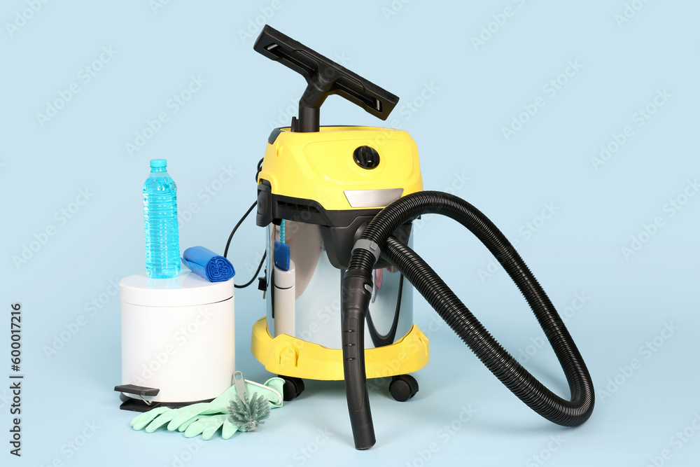 Vacuum cleaner with supplies and bin on blue background Vacuum cleaner with supplies and bin on blue background