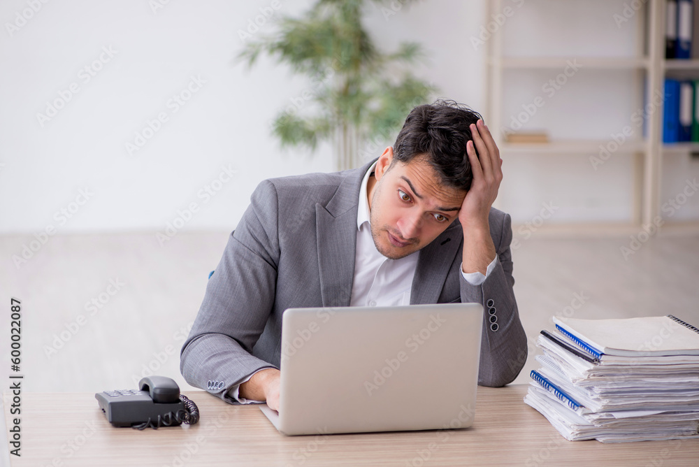Young male employee and too much work in the office Young male employee and too much work in the office