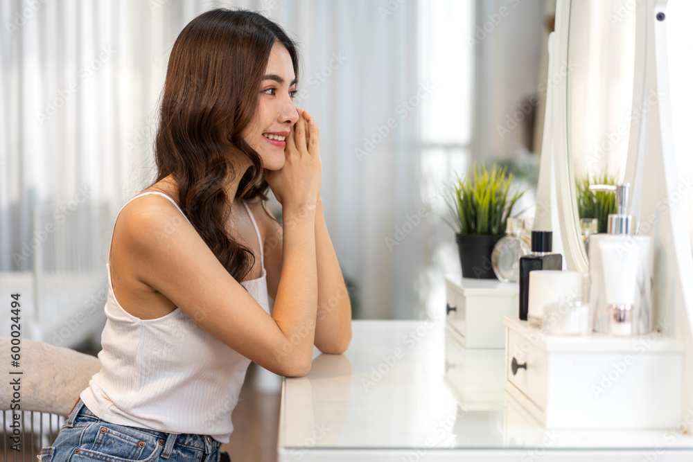 Smiling of beautiful asian woman fresh healthy white skin, clean, looking at mirror.asian girl touching on face applying cream, skincare, cosmetics, cosmetology, beauty, fashion at home.spa, wellness Smiling of beautiful asian woman fresh healthy white skin, clean, looking at mirror.asian girl touching on face applying cream, skincare, cosmetics, cosmetology, beauty, fashion at home.spa, wellness
