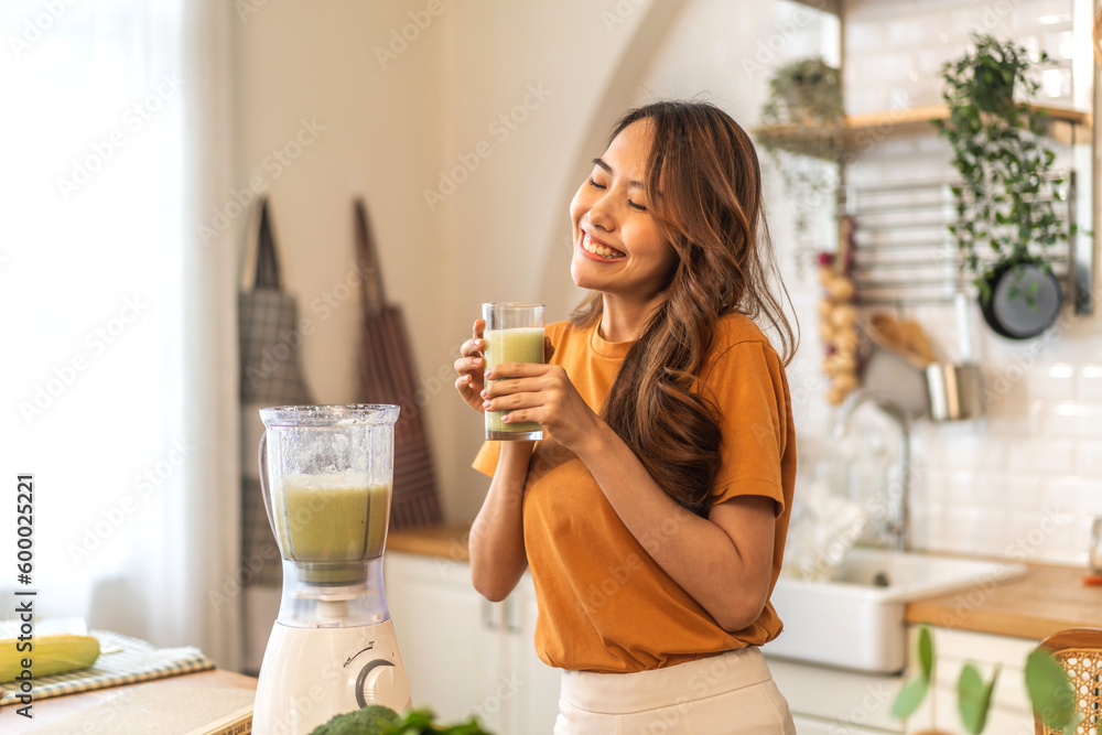 Portrait of beauty healthy asian woman making green vegetables detox cleanse and green fruit smoothie with blender.young girl drinking glass of green fruit smoothie in kitchen.Diet concept.healthy Portrait of beauty healthy asian woman making green vegetables detox cleanse and green fruit smoothie with blender.young girl drinking glass of green fruit smoothie in kitchen.Diet concept.healthy