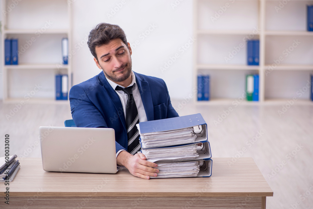 Young male employee and too much work in the office Young male employee and too much work in the office