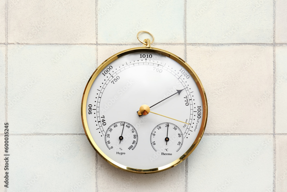 Aneroid barometer on white tiled background Aneroid barometer on white tiled background