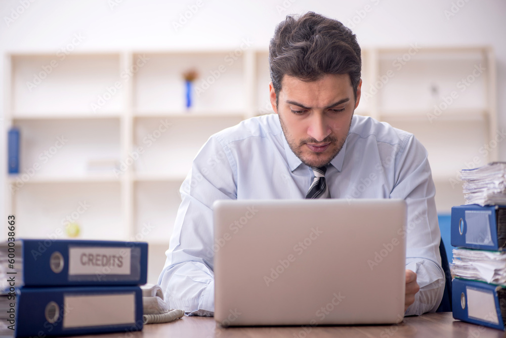 Young male employee and too much work in the office Young male employee and too much work in the office