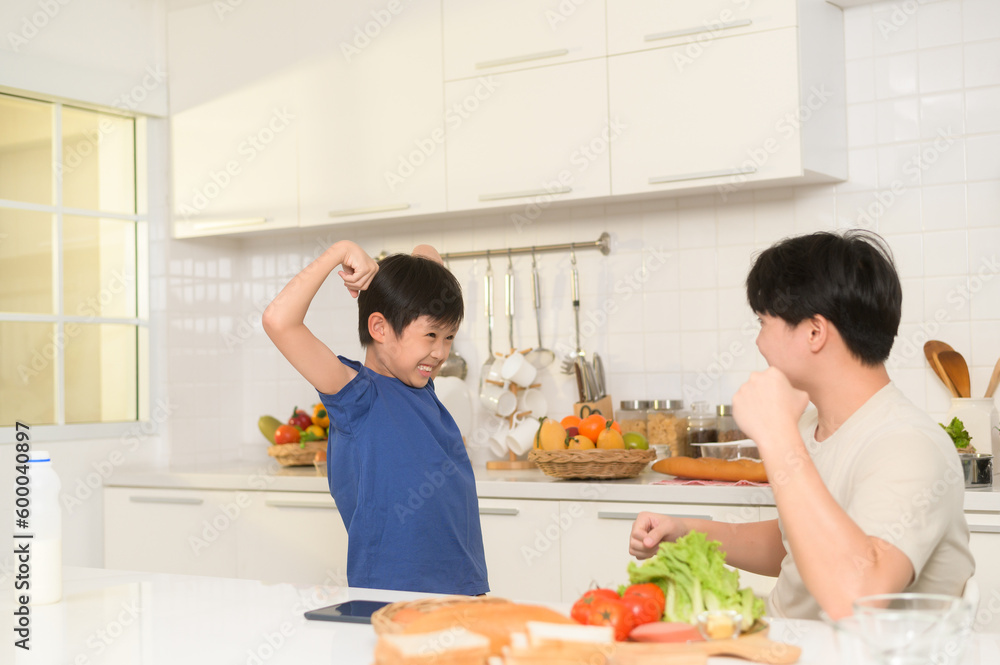 Asian boy showing strong arm , playful with his father in home