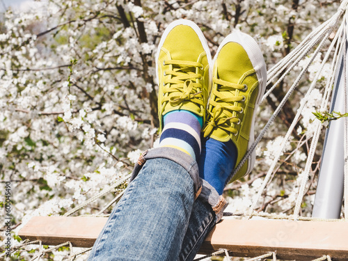 Trendy sneakers and colorful socks on the background of flowering trees. Closeup, outdoors. Men's and women's fashion style. Beauty and elegance concept