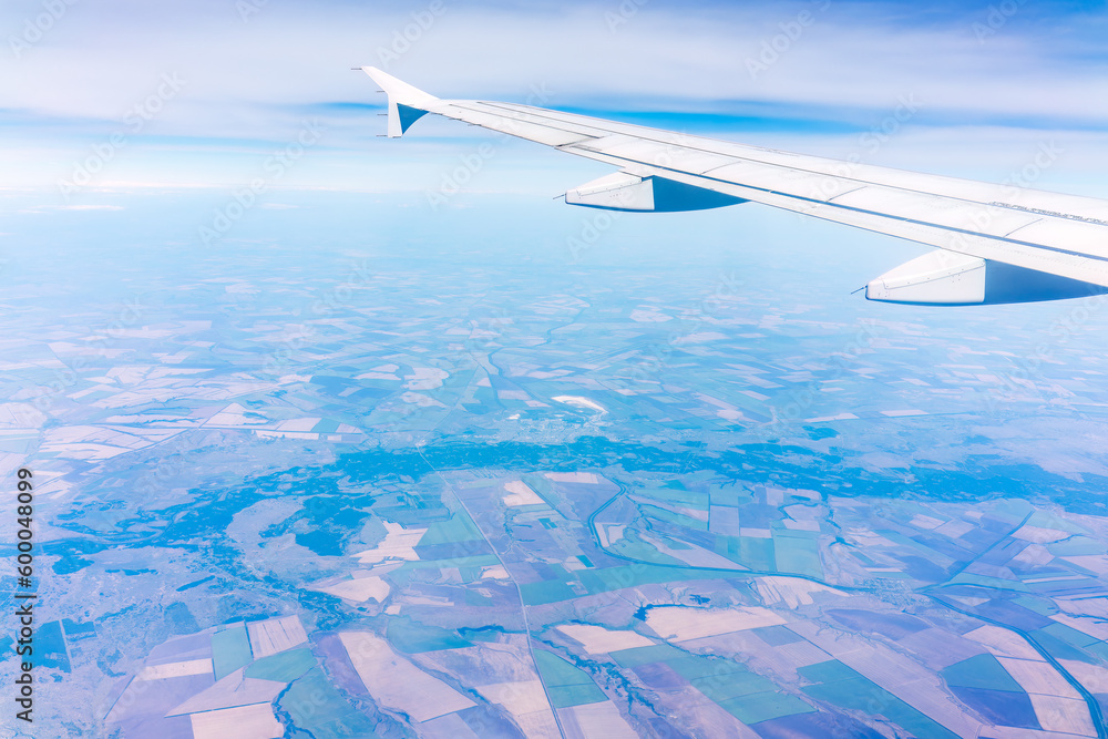 Aerial view from airplane window above green ground. View from the airplane window with beautiful clouds at sunrise Aerial view from airplane window above green ground. View from the airplane window with beautiful clouds at sunrise