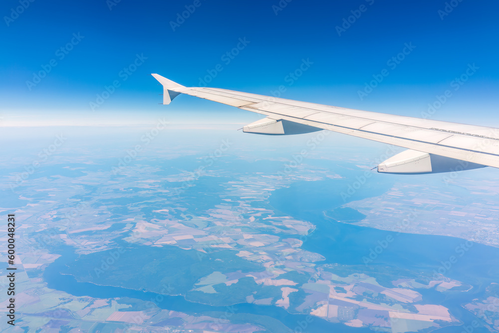 Aerial view from airplane window above green ground. View from the airplane window with beautiful clouds at sunrise Aerial view from airplane window above green ground. View from the airplane window with beautiful clouds at sunrise