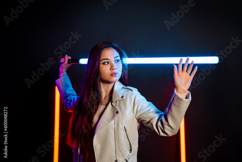Fotografie Futuristic game atmosphere with pretty asian woman holding lightsaber in neon lights