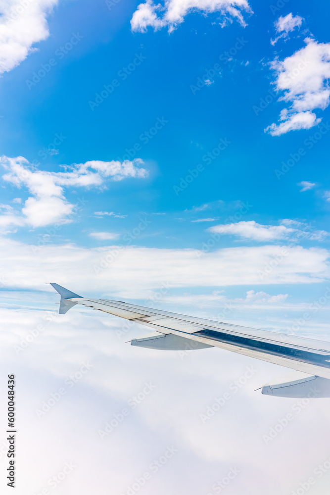 Fototapeta premium View from the airplane window at a beautiful cloudy sky and the airplane wing