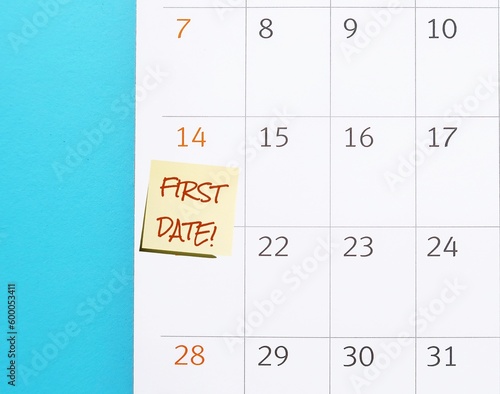 Calendar on blue background with handwritten note FIRST DATE meeting appointment during dating process to learn about two people, romantic activity which both expect to have relationship in future