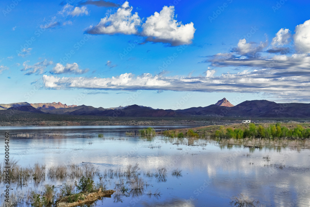 Panoramic view over the Rawhide Mountains and Alamo Lake in the morning sun, Arizona, USA. Recreational vehicle parked on a headland in the distance.
