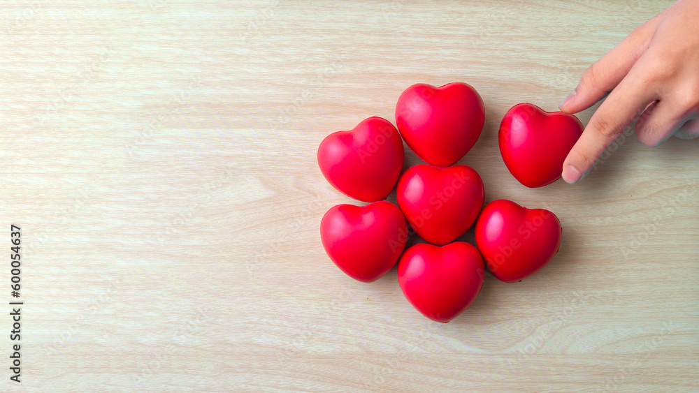 Adult hands putting red heart on woodden background , health care, organ donation, world heart day, world health day, praying concept Adult hands putting red heart on woodden background , health care, organ donation, world heart day, world health day, praying concept