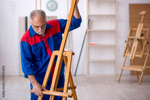 Old male carpenter repairing drawing easel