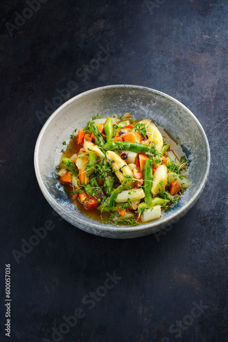 Green and white asparagus glazed with papaya in sweet vinaigrette served as close-up in a design plate with text space