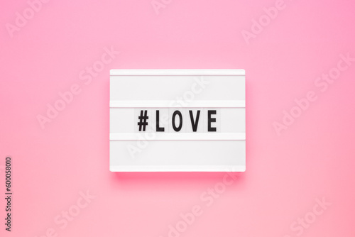 The word love on lightbox isolated pink background. Happy Valentines day concept. Romantic flat lay composition