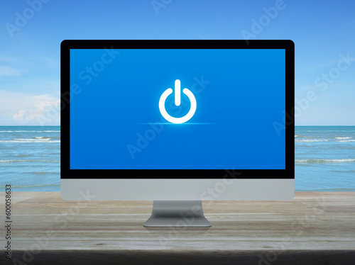 Power button icon on desktop modern computer monitor screen on wooden table over tropical sea and blue sky with white clouds, Business start up online concept
