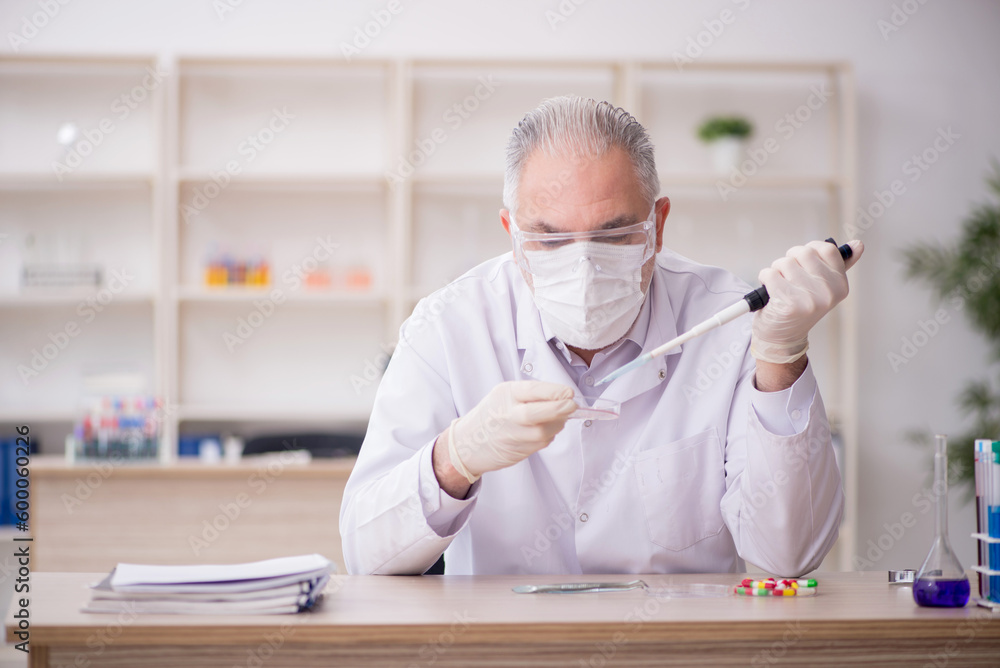 Old male chemist working at the lab