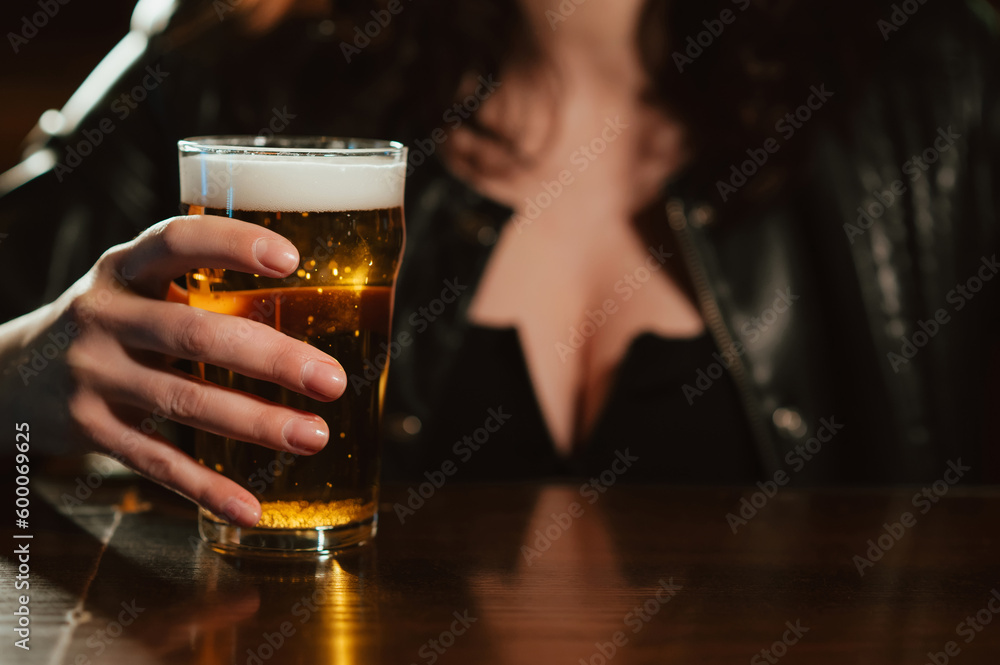 woman with big breasts holds a glass of beer lager with foam in her hand at bar