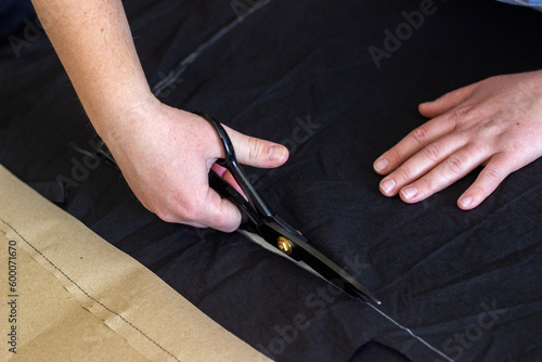 the process of cutting black fabric. Close-up of a seamstress's hands. cutting of cloths. Cutting and sewing courses. 