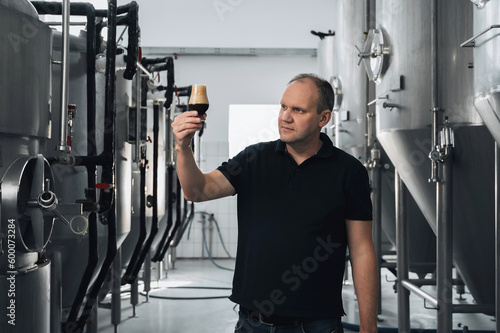 brewer at brewery checks the quality with a glass of fresh beer