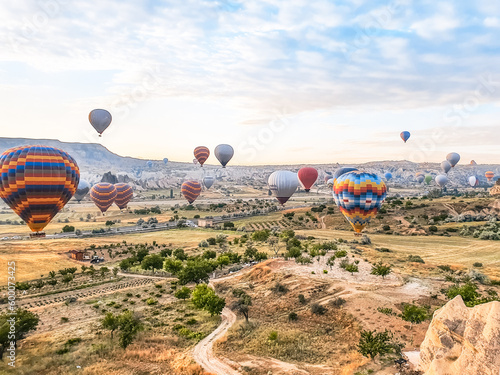 Flying in sky many bright colored beautiful balloons into air in Cappadocia in mountains early at sunrise, dawn. Filling balloon with hot air from burner, big basket. Tourists excursion, cloud flight © velirina