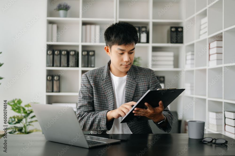 Asian business man executive manager looking at laptop watching online webinar training or having virtual meeting video conference doing market research working in modern office. Asian business man executive manager looking at laptop watching online webinar training or having virtual meeting video conference doing market research working in modern office.