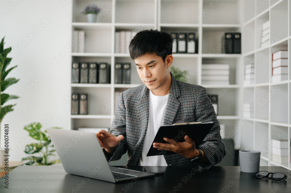 Fototapeta premium Asian business man executive manager looking at laptop watching online webinar training or having virtual meeting video conference doing market research working in modern office.