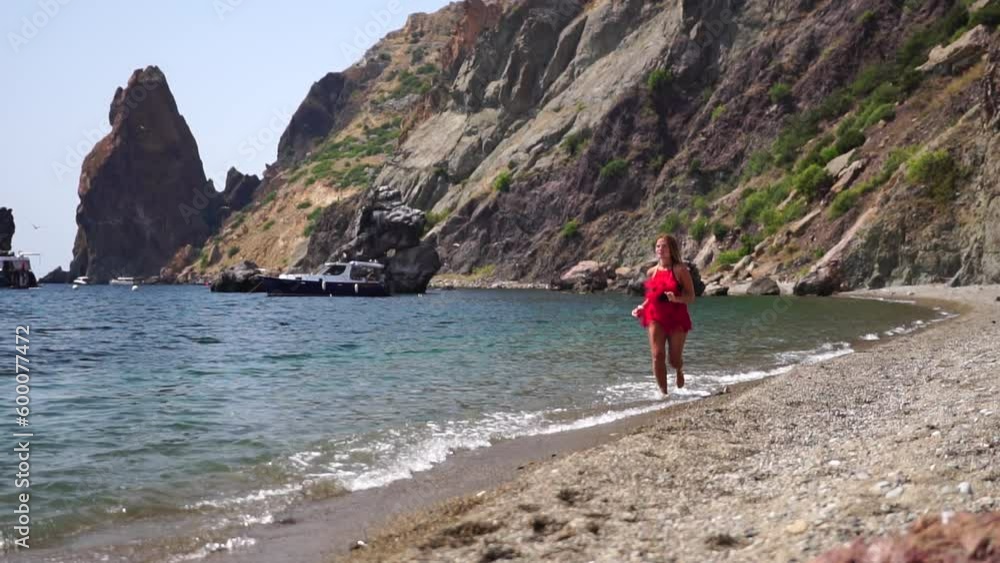 Woman sea travel. Happy middle aged sporty woman with long hair, fitness instructor in red swimwear enjoys the scenery in the mountains near sea. Female fitness trekking concept. Woman sea travel. Happy middle aged sporty woman with long hair, fitness instructor in red swimwear enjoys the scenery in the mountains near sea. Female fitness trekking concept.