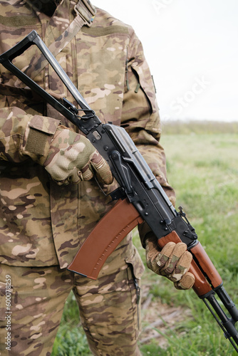 Military man holding AK-47 with tactical gloves