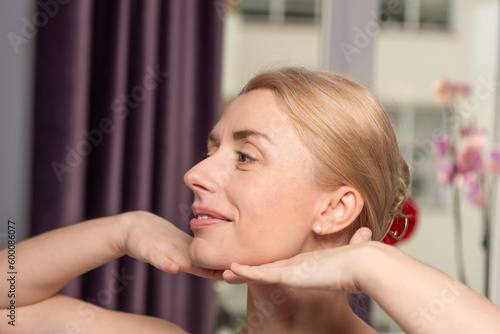 A young woman makes a face self-massage for the effect of lifting and rejuvenation