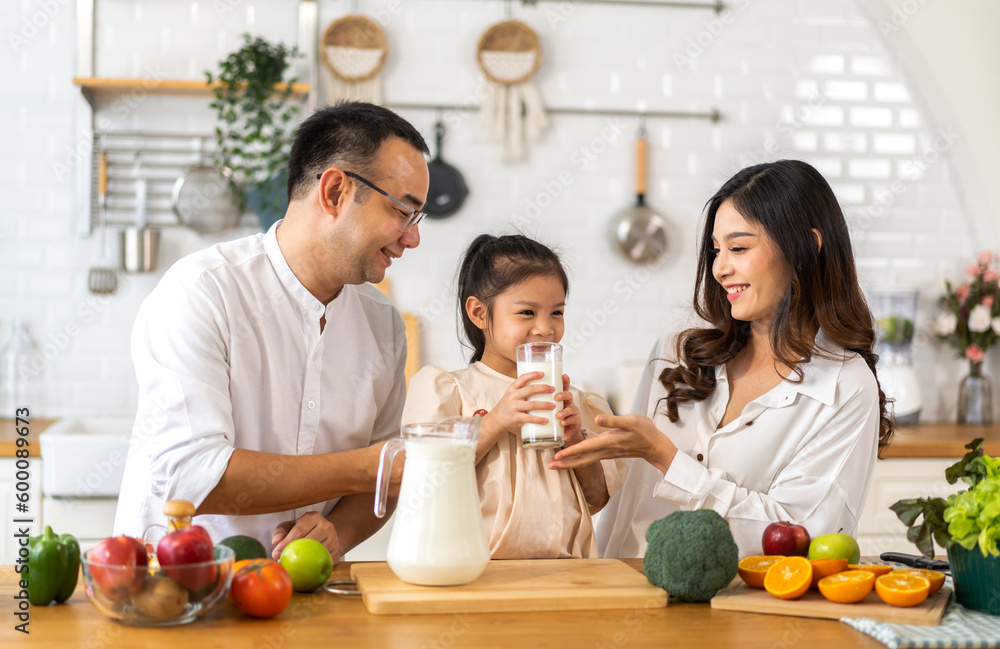 Portrait of happy love asian family father and mother with little girl smiling and having protein breakfast drinking hold glasses of milk,healthy nutrition,calcium,vitamin,dairy product,strong,growth