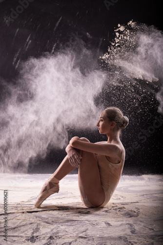 Ballerina on a black background with a cloud of white flour.