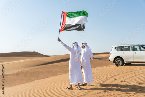 Two middle-eastern emirati men wearing arab kandura bonding in the desert