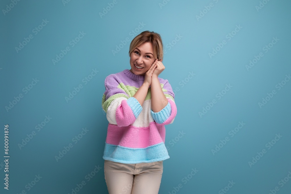 close-up of an embarrassed blond young woman in a striped sweater on a blue background with copy space close-up of an embarrassed blond young woman in a striped sweater on a blue background with copy space