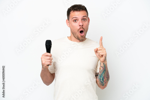 Young caucasian singer man picking up a microphone isolated on white background intending to realizes the solution while lifting a finger up