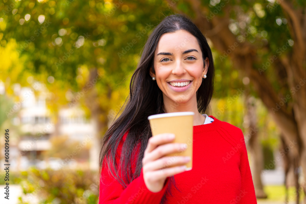 Young woman holding a take away coffee at outdoors with happy expression Young woman holding a take away coffee at outdoors with happy expression