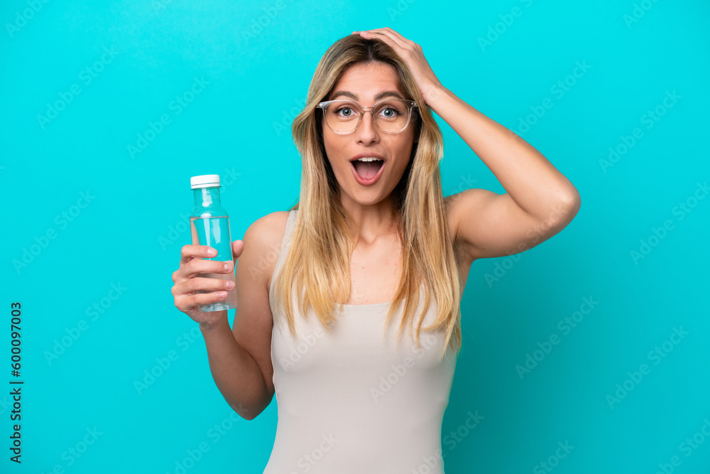 Young Uruguayan woman with a bottle of water isolated on blue background with surprise expression Young Uruguayan woman with a bottle of water isolated on blue background with surprise expression