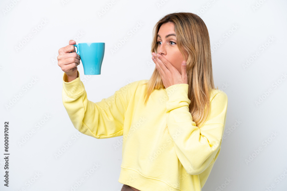 Young Uruguayan woman holding cup of coffee isolated on white background with surprise and shocked facial expression Young Uruguayan woman holding cup of coffee isolated on white background with surprise and shocked facial expression
