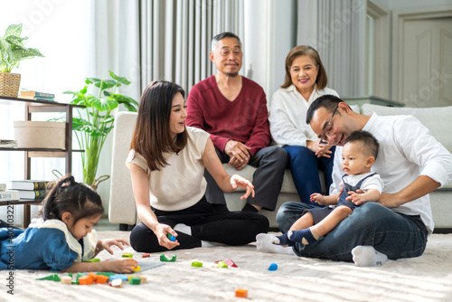 Portrait of enjoy happy love asian big family father and mother with little asian girl smiling activity learn and skill brain training play with toy build wooden blocks board education game at home