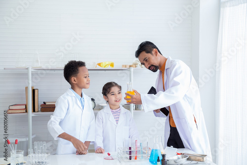 Science laboratory education for kids concept, cute cheerful students having fun with a chemistry lab test, multi diversity pupils in white gown uniform acting professional scientists in the classroom
