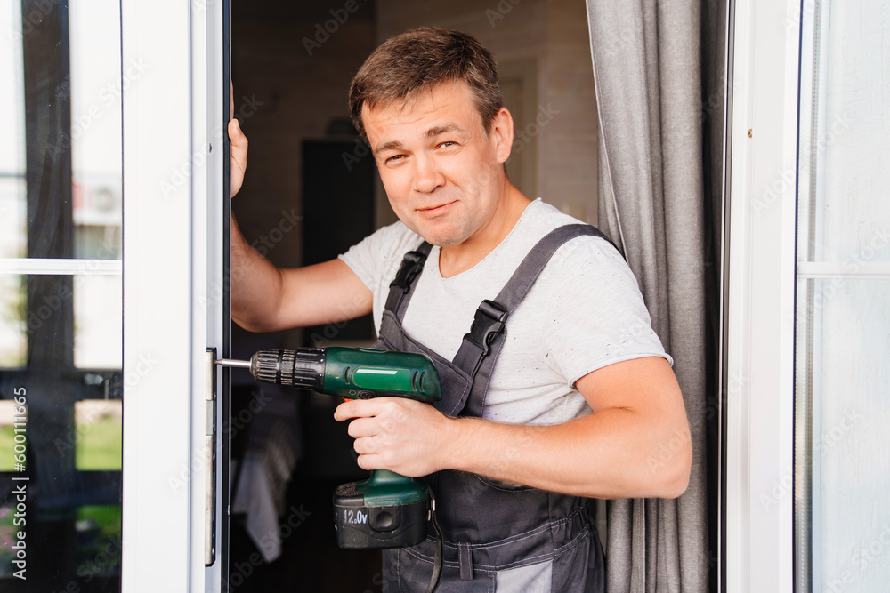 A repairman repairs or adjusts window frames or glass doors on the terrace. A repairman repairs or adjusts window frames or glass doors on the terrace.