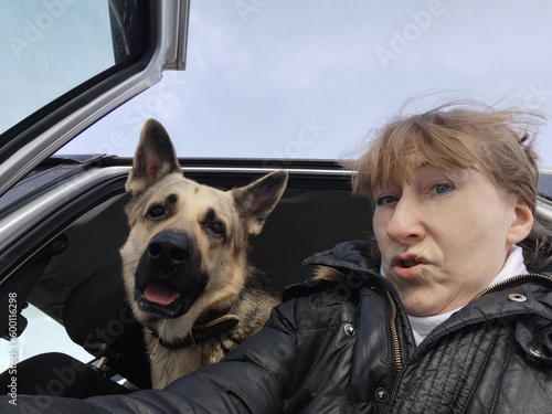 An adult girl and a dog in a car. The journey of a woman and an animal. Friendship of a shepherd pet and a mature lady photo