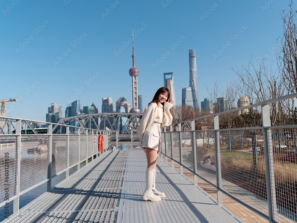 Φωτογραφία Beautiful young woman with black long hair in white skirt smiling with Shanghai city bund landmarks background in sunny day