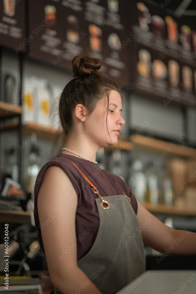 Portrait of a young beautiful barista girl in a coffee shop.