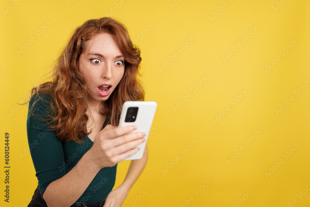 Surprised redheaded woman looking the screen of a mobile Surprised redheaded woman looking the screen of a mobile