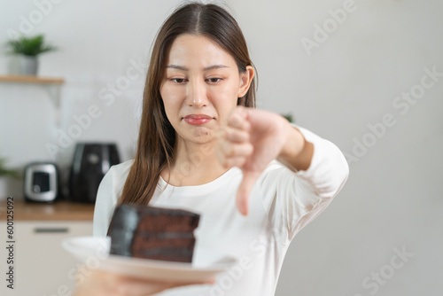 Diet asian young woman hand showing thumb up refusing to eat the chocolate cake or sweet taste, fighting to keep it from getting fat when people giving to me. Health care, nutrition of weight loss.