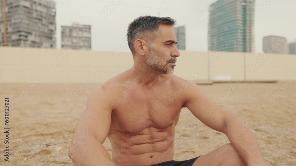 Mature man is resting sitting on the sand on the coast Mature man is resting sitting on the sand on the coast